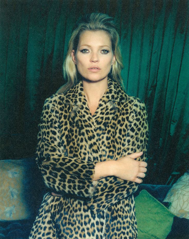 Kate Moss in a leopard-print coat in front of green velvet curtains